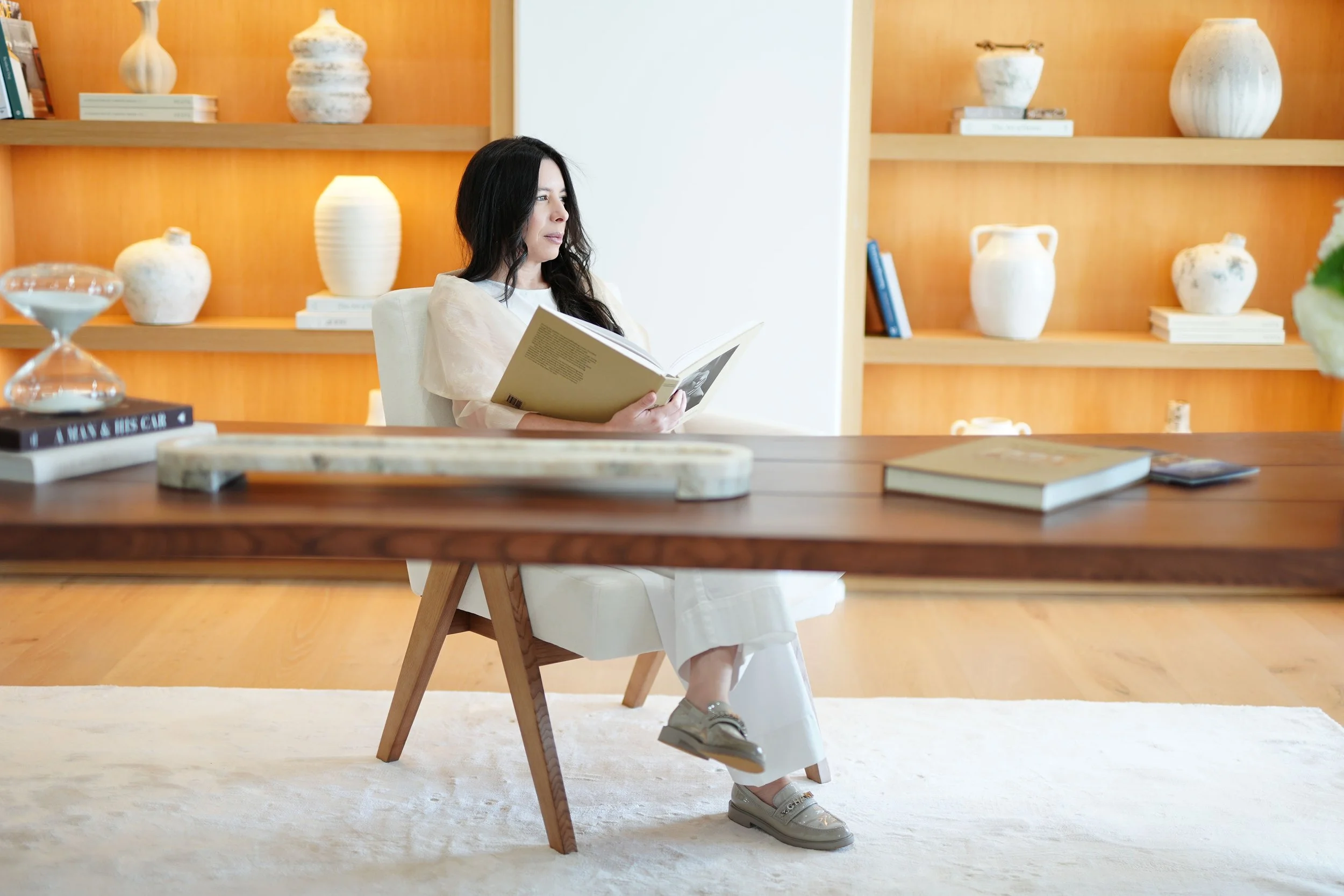 Vânia Aquino at a wood desk with illuminated shelving, home office inspiration