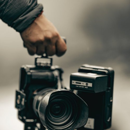 A hand lifting a cinema camera