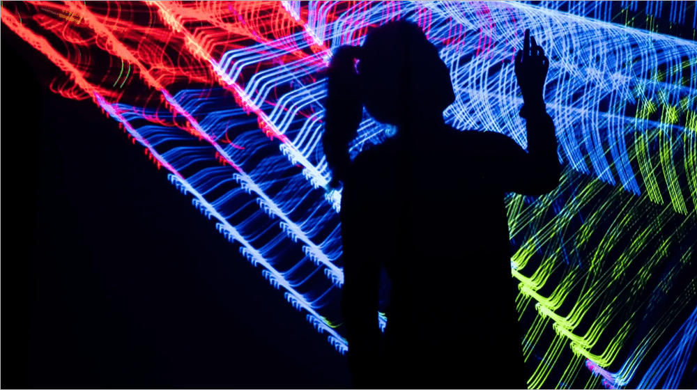 A silhouette with a hand raised into laser light