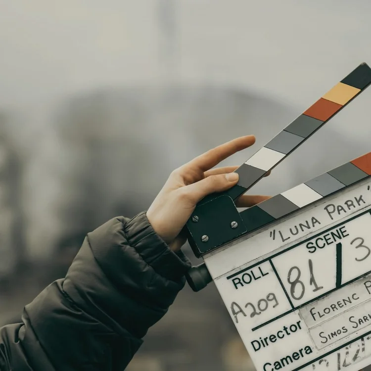 A hand holding a film clapperboard