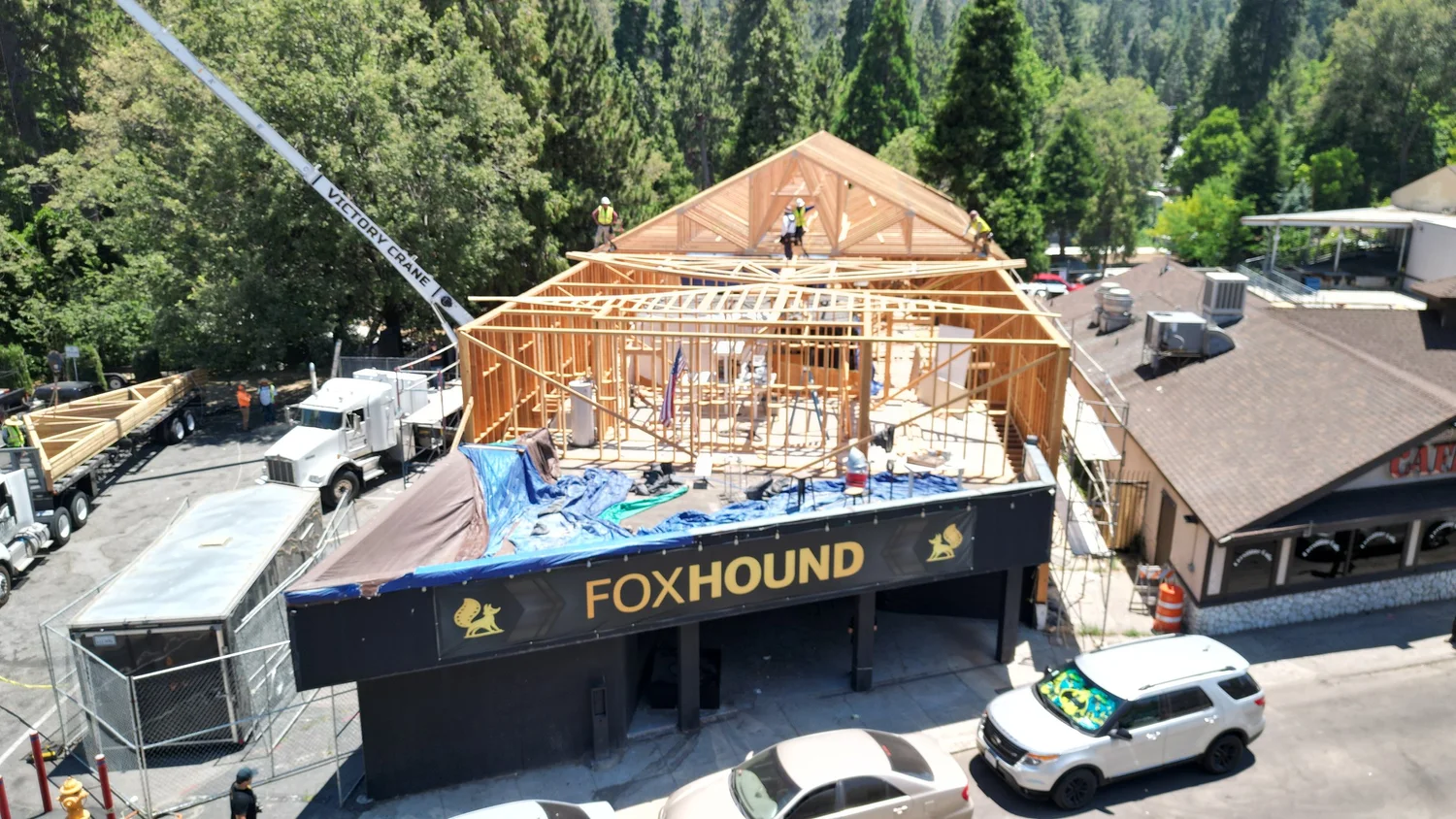 Aerial view of a crane lifting new roof framing over the building
