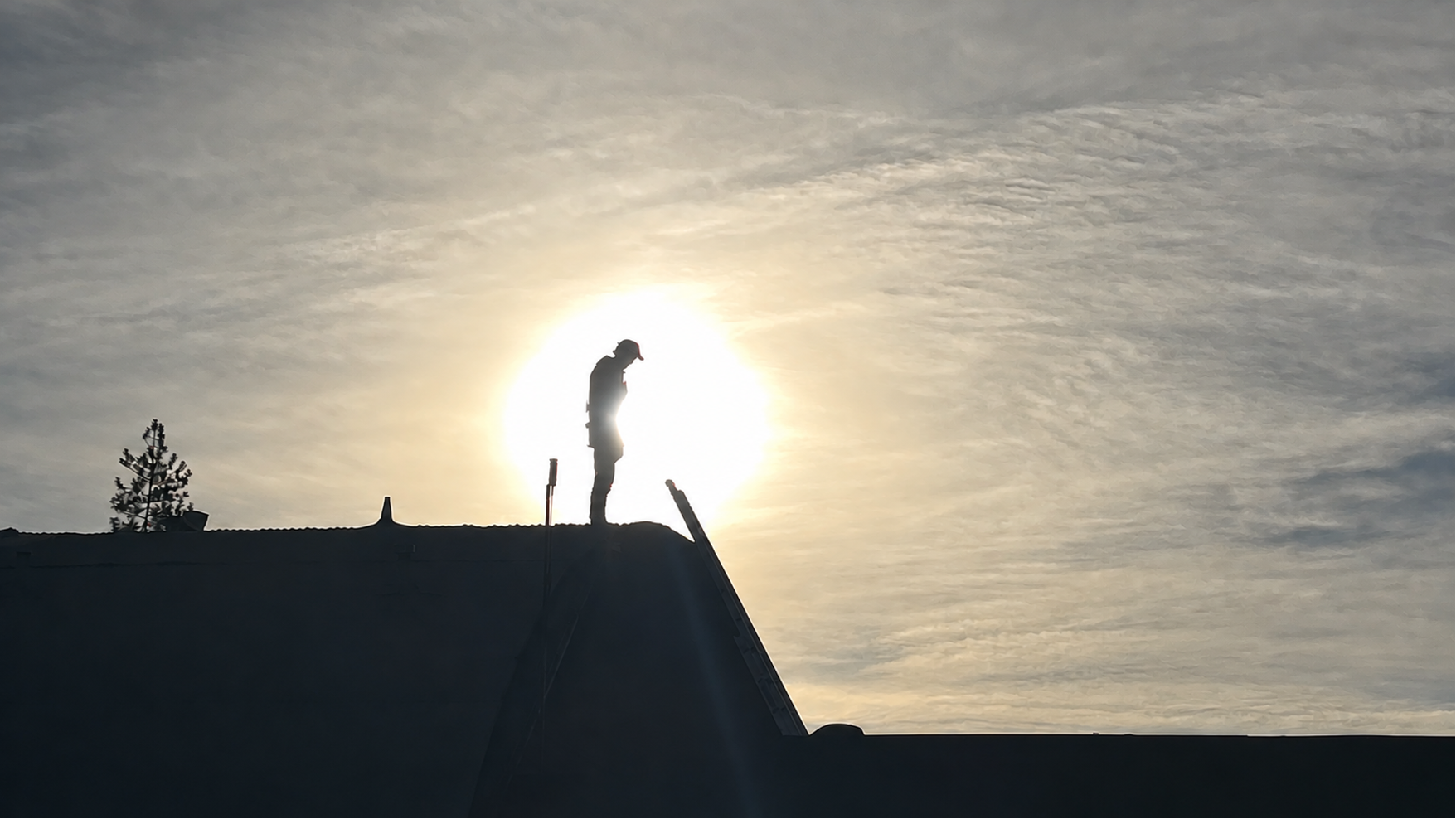 Jonathan standing in silhouette on the roof after the collapse, with the sun behind him