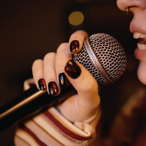 A hand holding a microphone mid-song