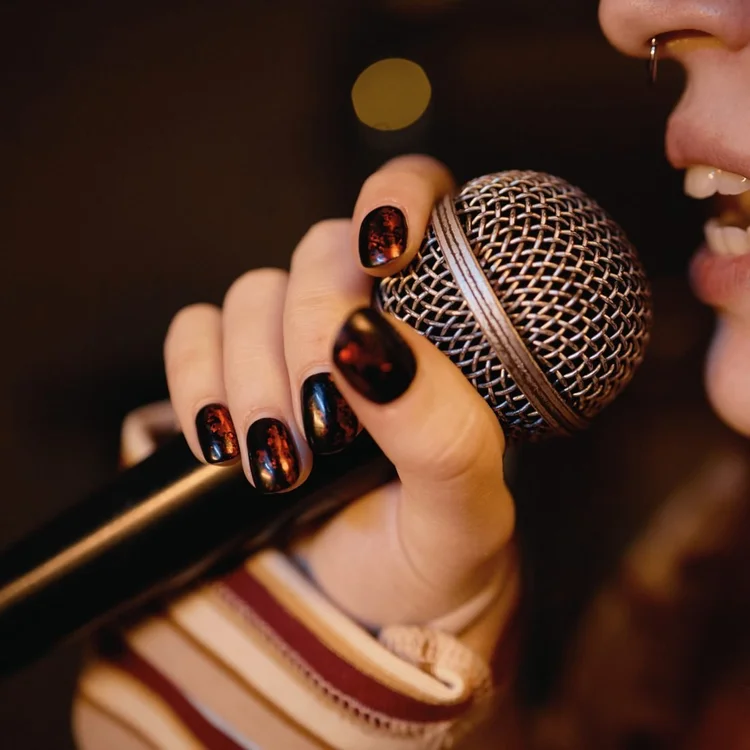 A hand holding a microphone mid-song