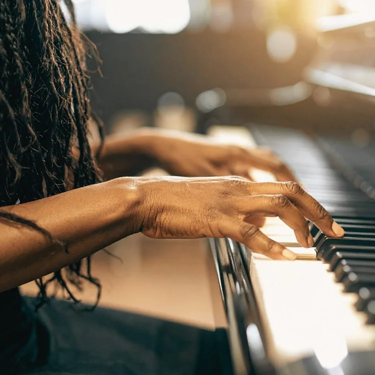Hands playing a piano in warm light