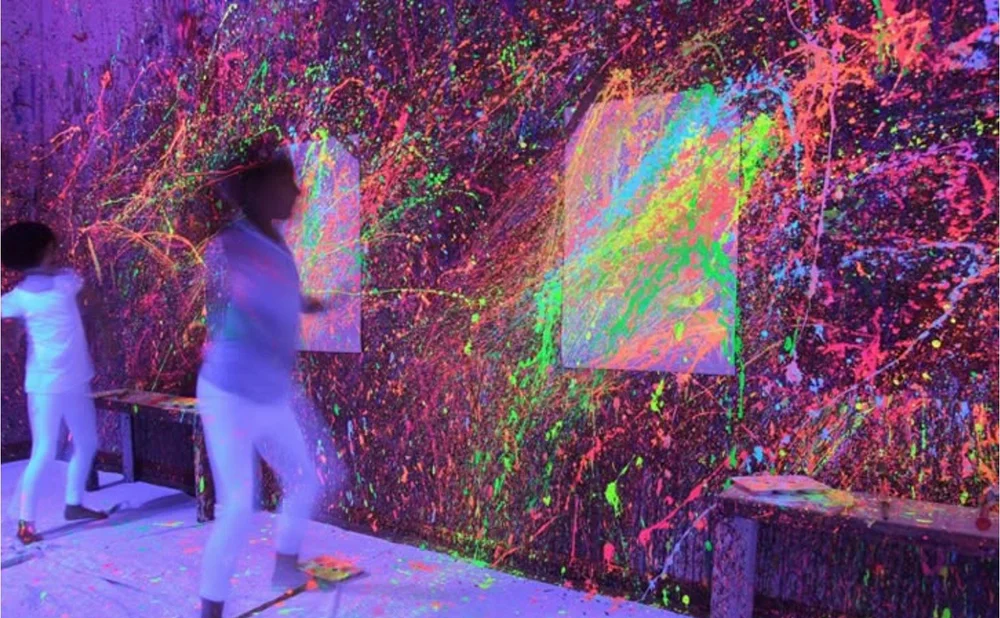 People throwing neon paint at a wall