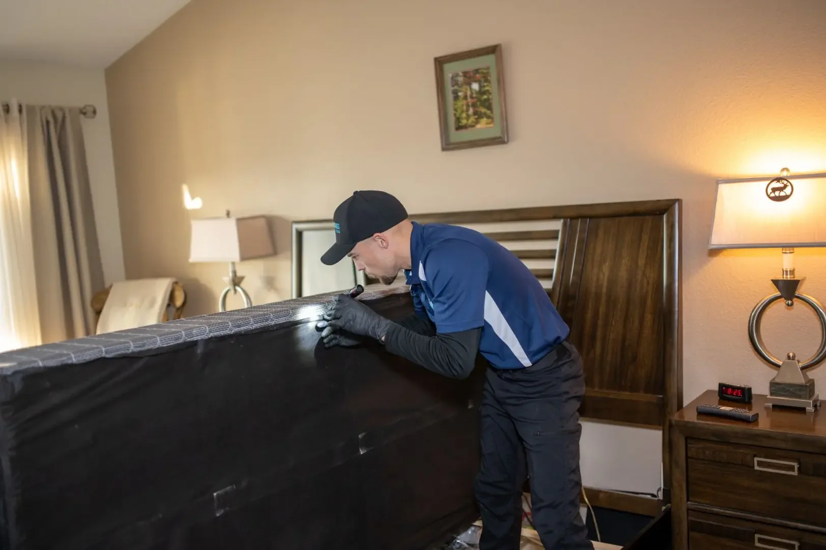 Bed bug inspection of a bed with a flashlight, Hotel & Motel Bed Bug Treatment in Phoenix, AZ