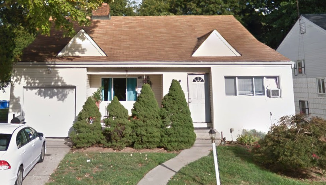 Catlin Avenue property in Roosevelt, a white house with an attached garage and shrubs in the front yard