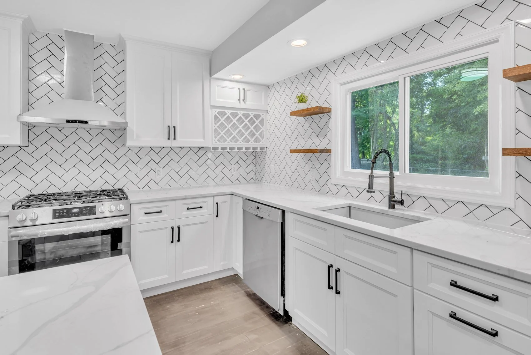 Renovated white kitchen with herringbone tile backsplash and quartz counters