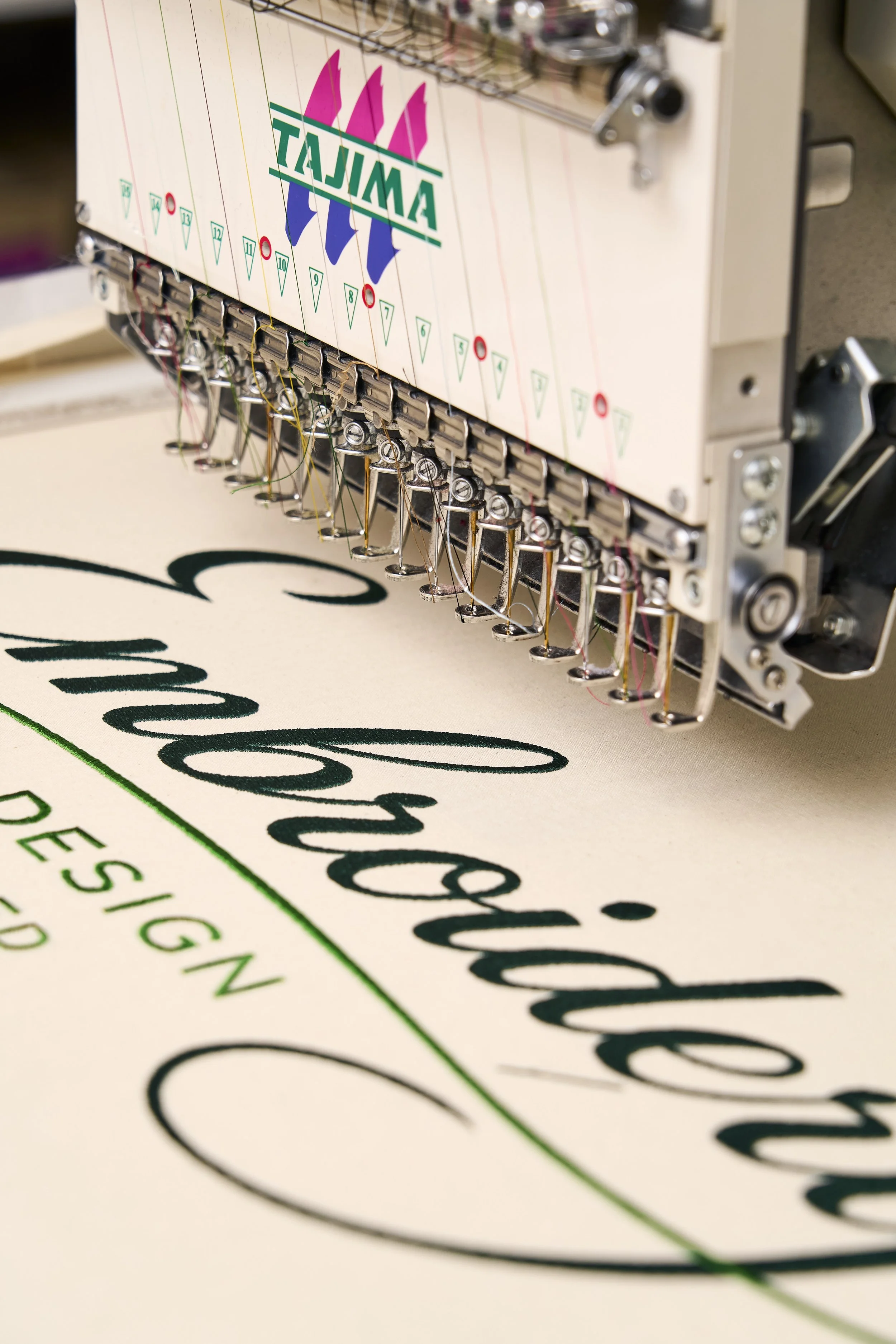 Close-up of the Tajima multi-needle embroidery machine working on lettering