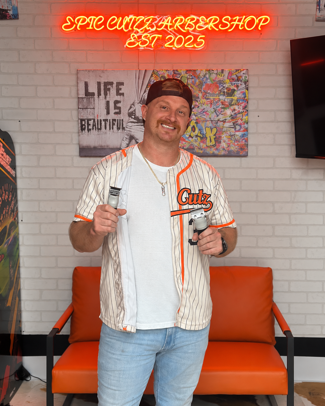 Anthony Genovese, owner of Epic Cutz Barbershop, holding barber scissors and clippers