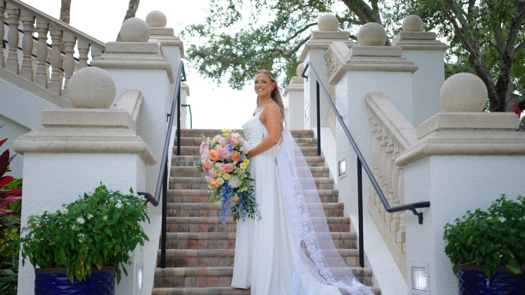 Bride holding a colorful bouquet on a garden staircase