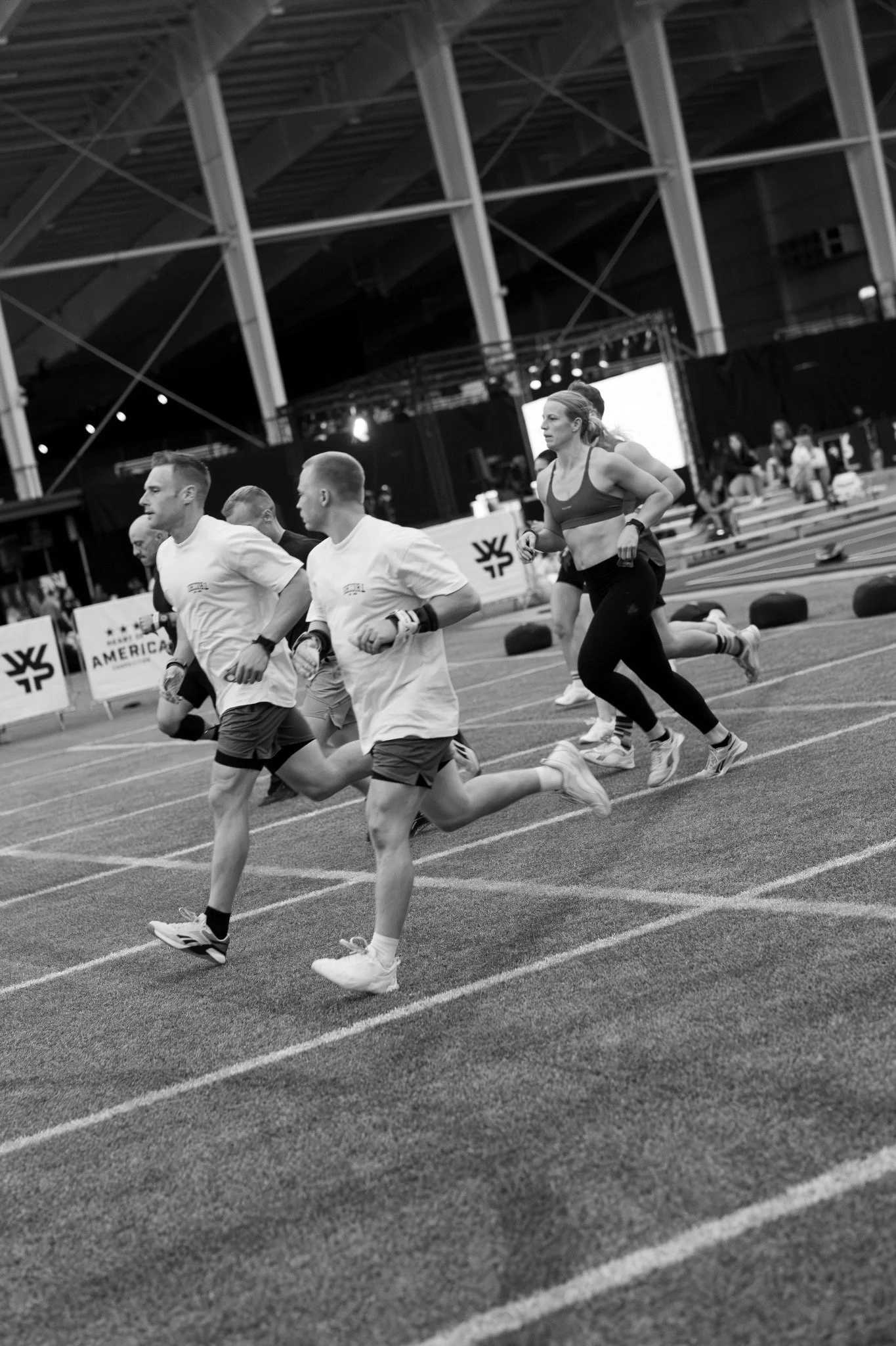 Black and white photograph of athletes running in a gym
