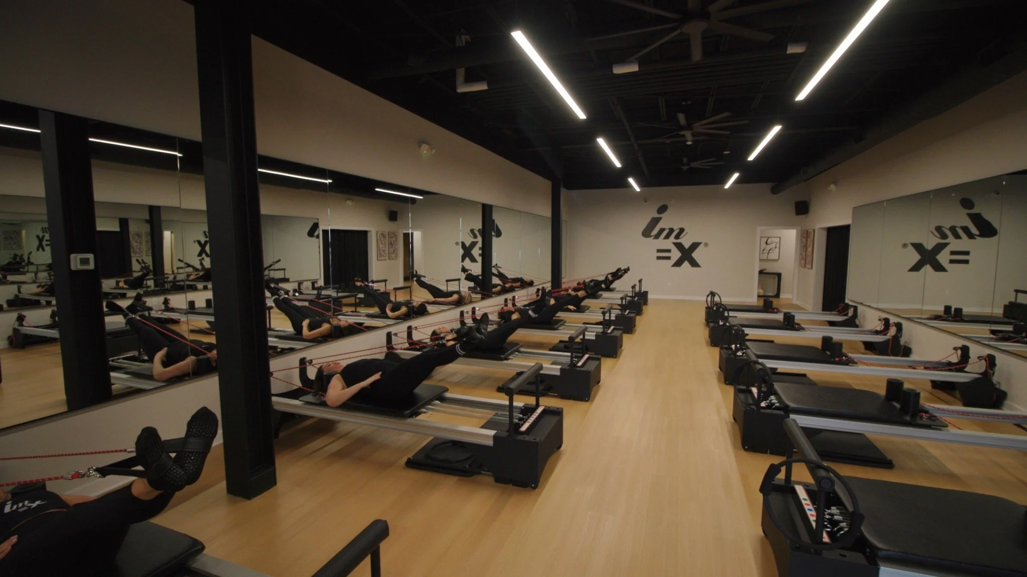Group Pilates class in a mirrored reformer studio