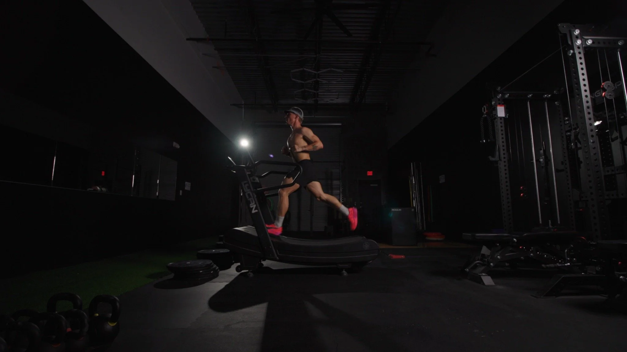 Runner training on a curved treadmill in a dramatically lit gym