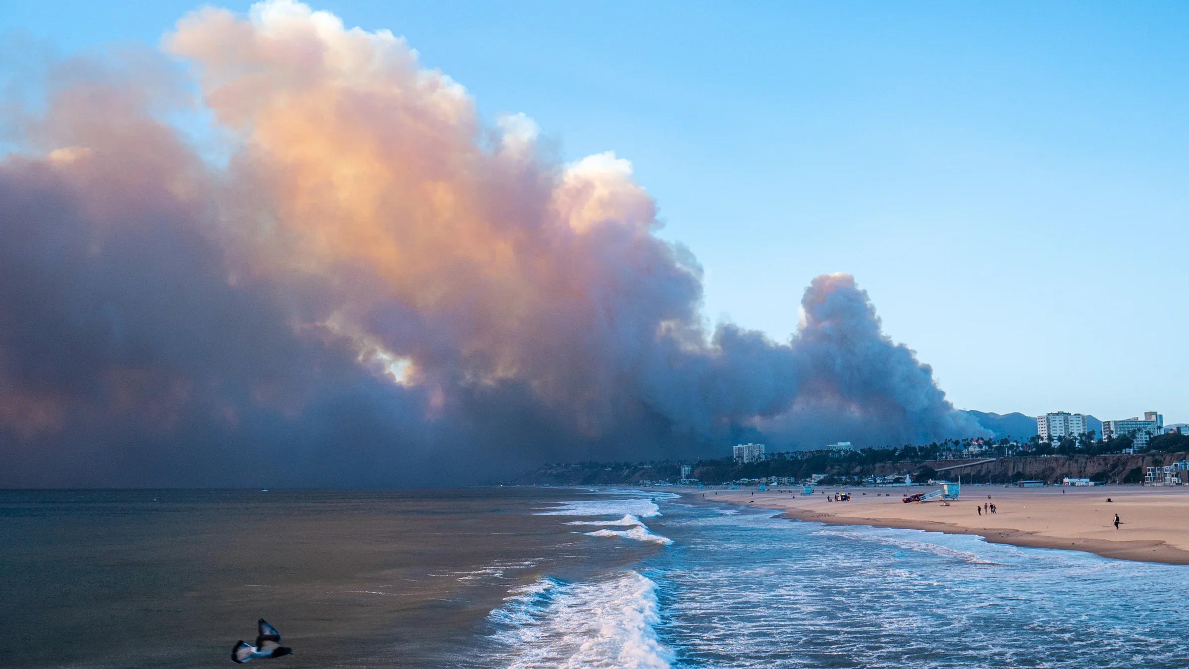 A large wildfire smoke plume moving over a Southern California coastal community