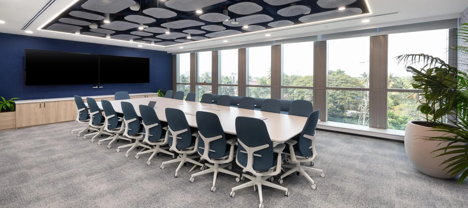 Illustrative conference room with a long meeting table, blue task seating, and large windows