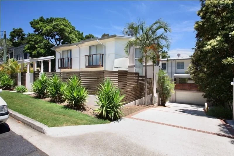 The townhouses from the street, behind a timber-slat fence and garden