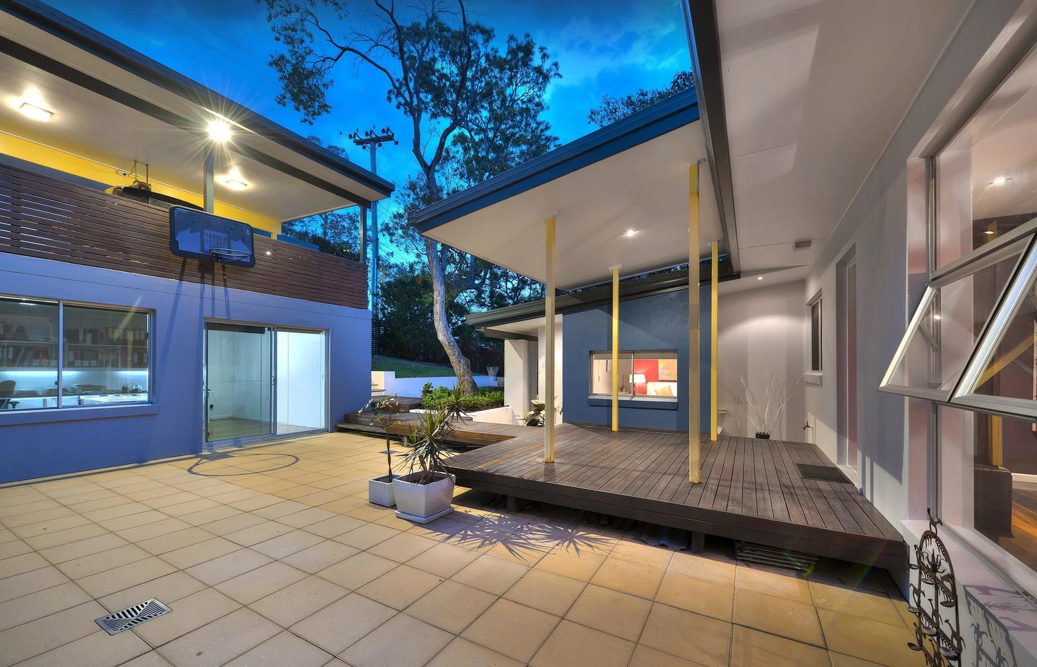 Paved courtyard and timber deck under a broad roof at dusk
