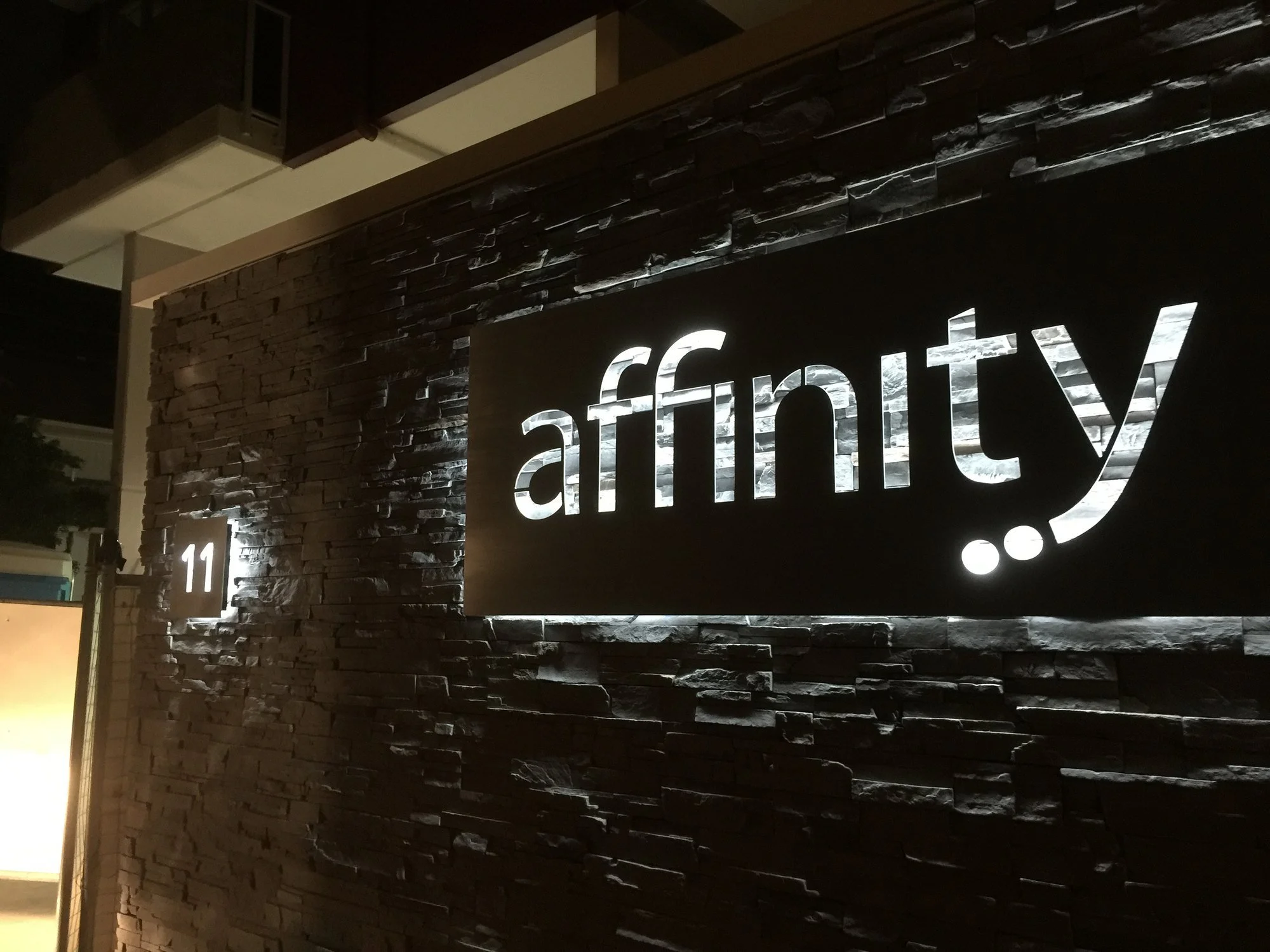 The illuminated Affinity sign on the stone feature wall