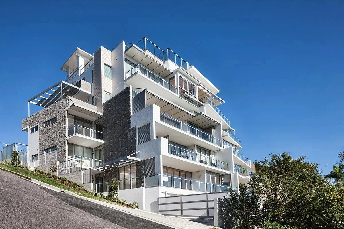 Envisage Apartments seen from the street, white terraces stepping up a steep site under a clear blue sky