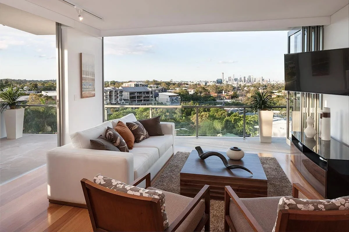 Living room opening to a terrace with the city on the horizon