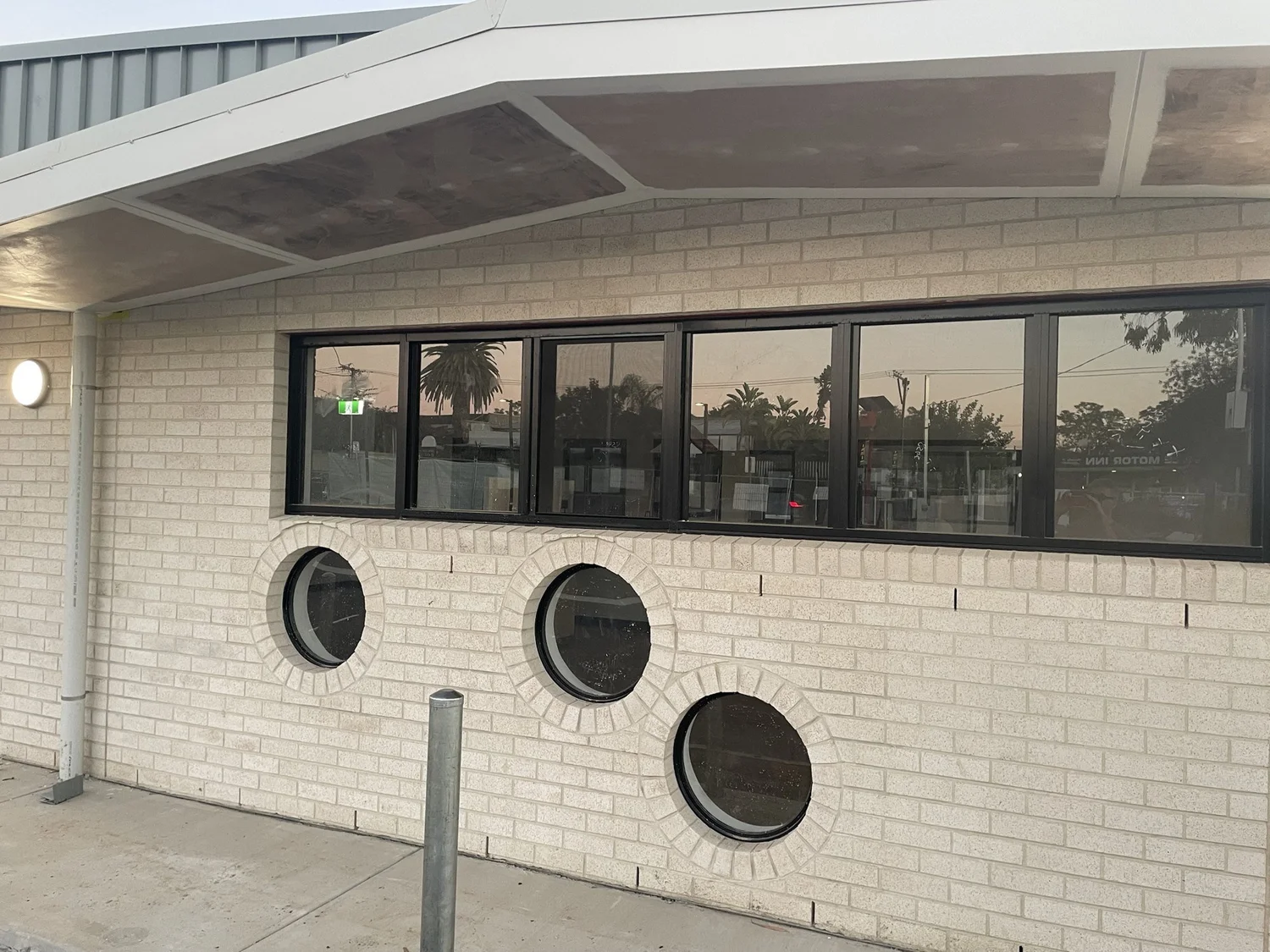 Three round windows set into the brick wall below a strip window