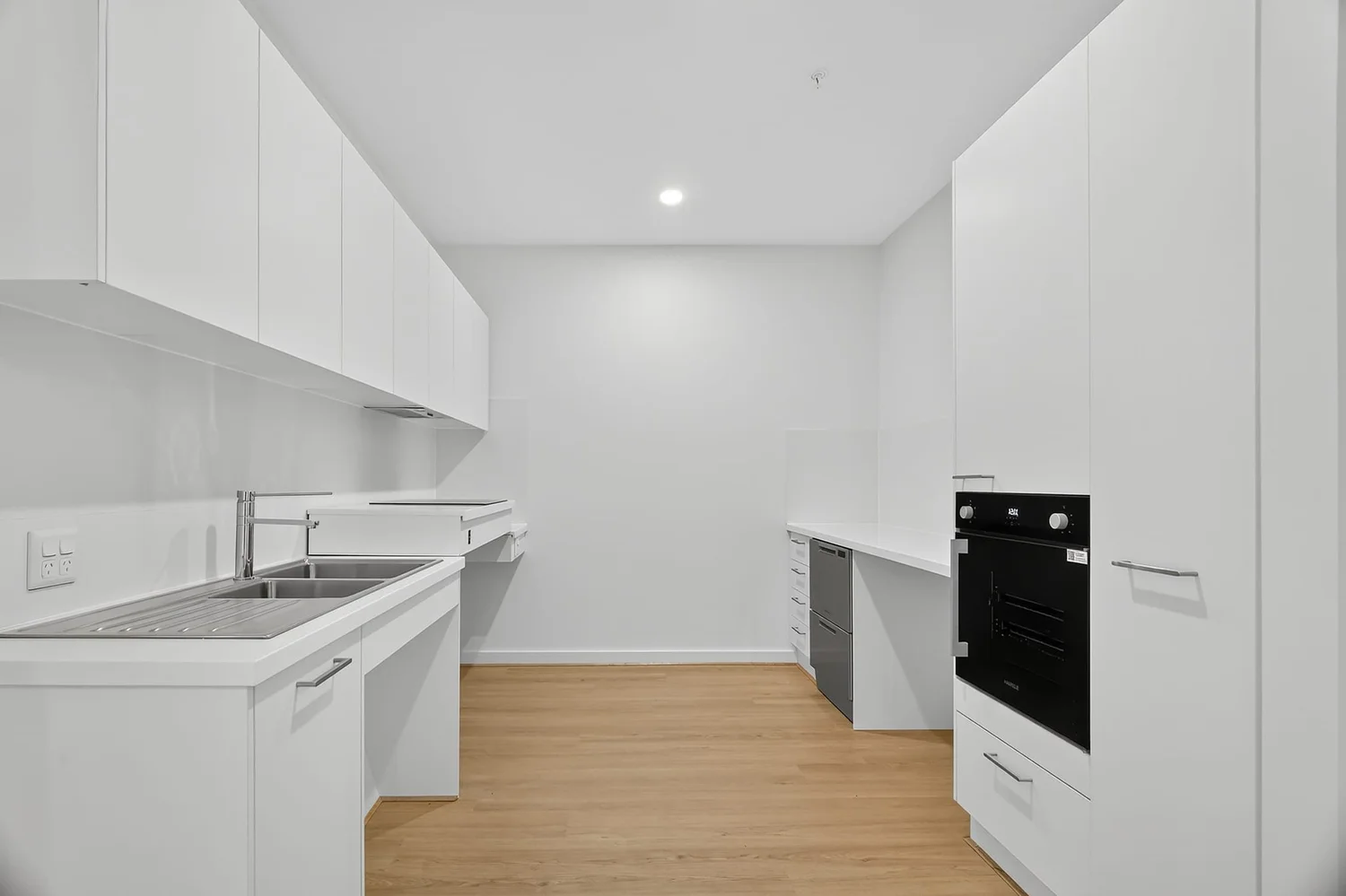 Galley kitchen with a wall oven, drawer dishwasher and sink bench, with knee space beneath the bench