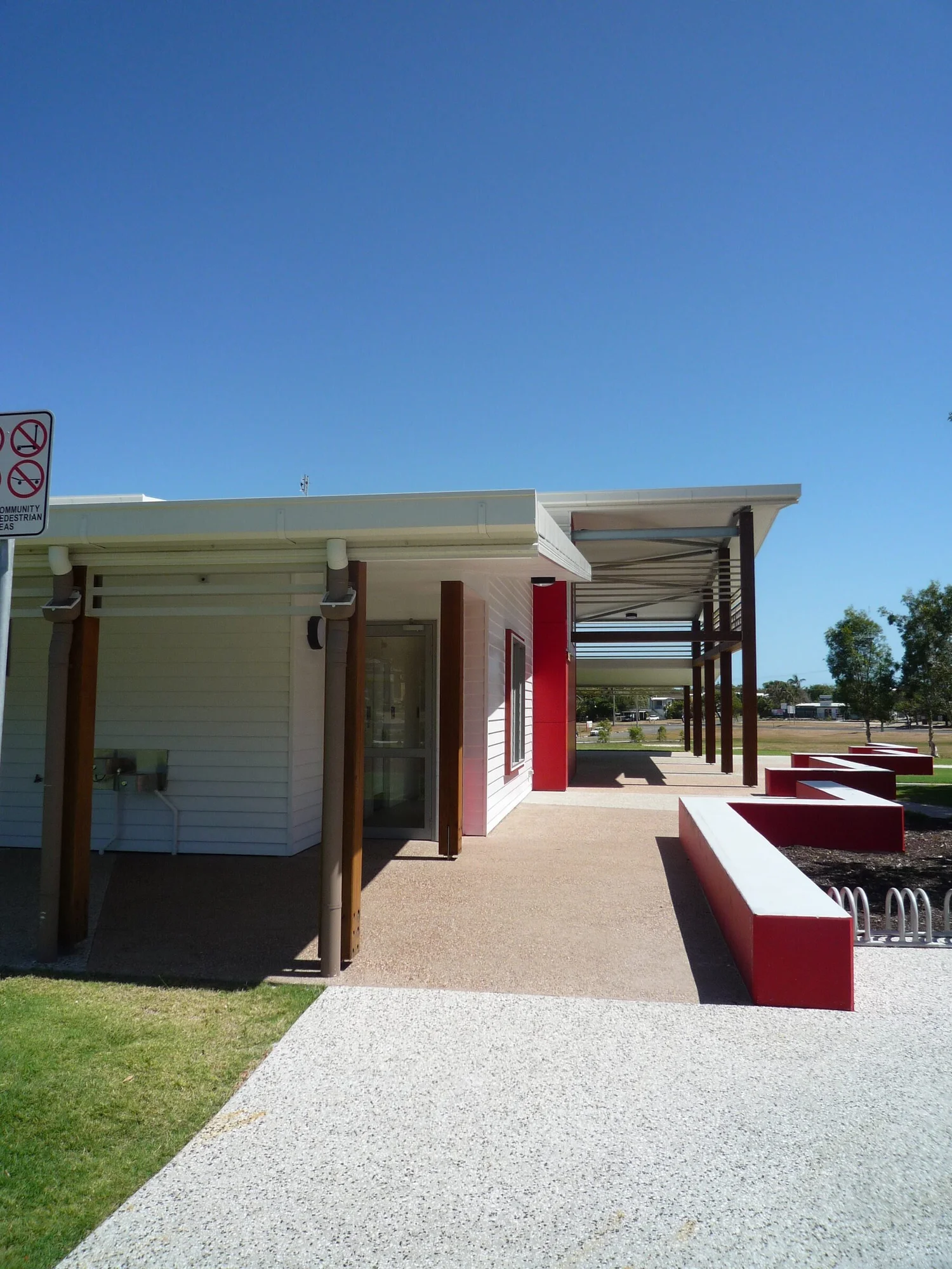 The entry path between the red wall and the timber posts