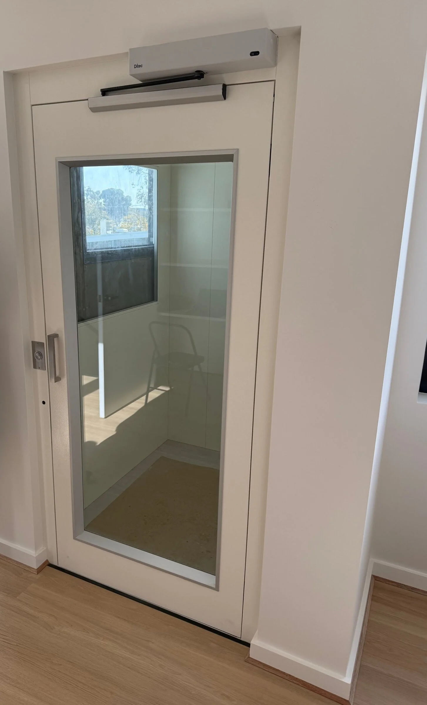A glazed lift door with an automatic opener, looking into the lift car