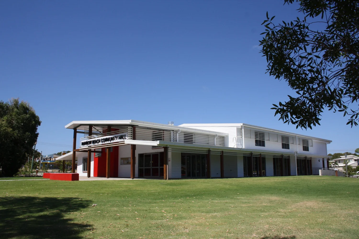 The hall across its lawn, with the verandah and the red entry wall