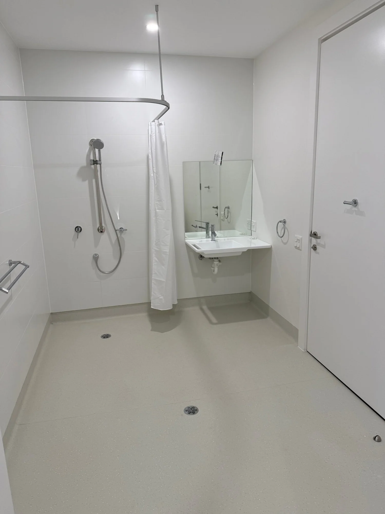 The accessible bathroom: step-free shower with grab rail and hand shower, and a wall-hung basin