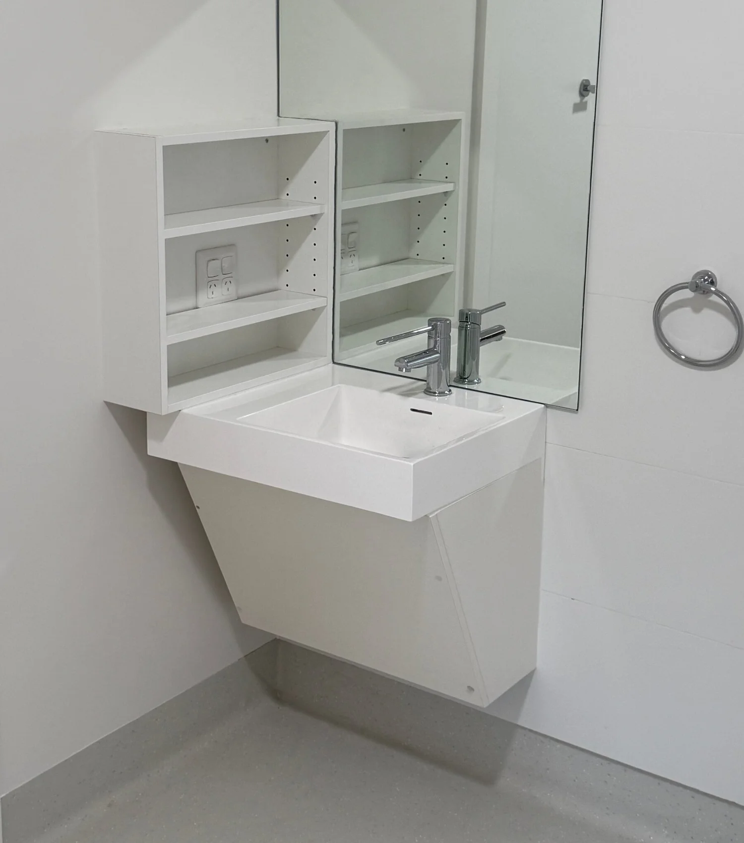 Wall-hung basin with open shelves and a mirror, with clear space beneath for a wheelchair