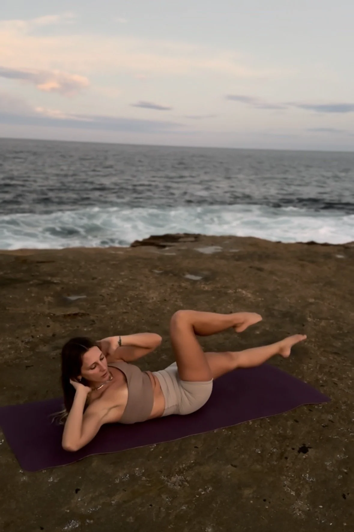 Francesca’s mat Pilates practice beside the ocean, shown in a laptop frame