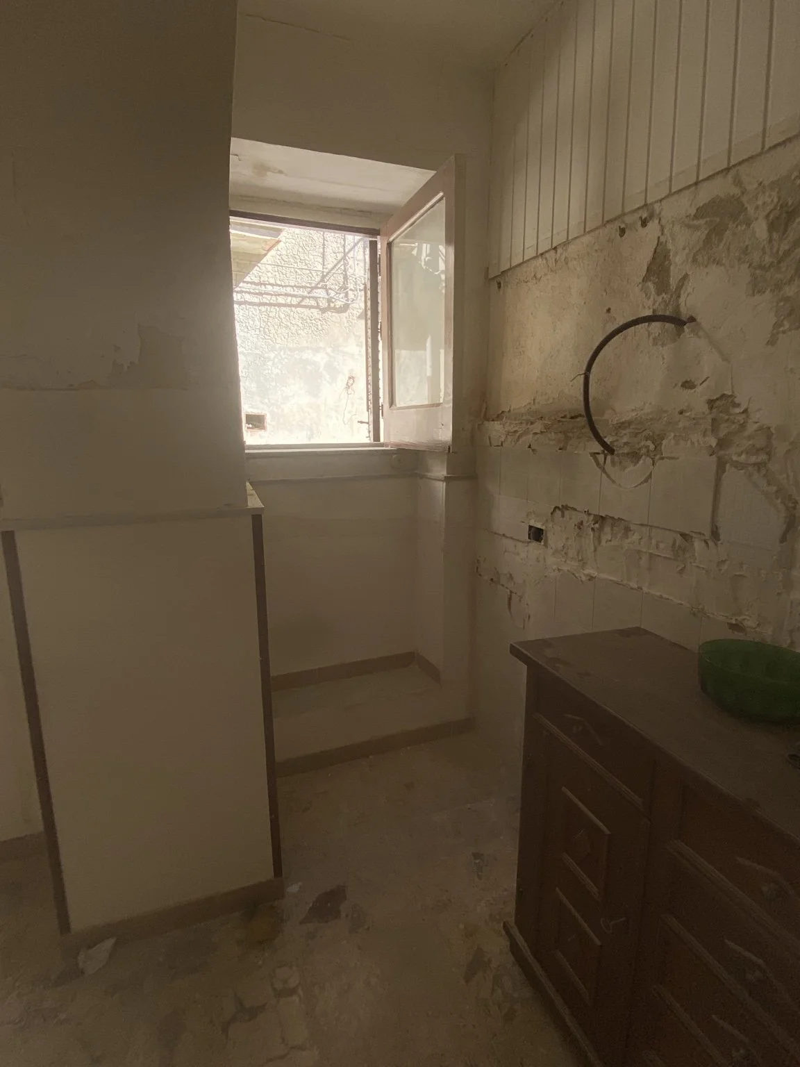 An open window above a small step, beside a stripped wall.