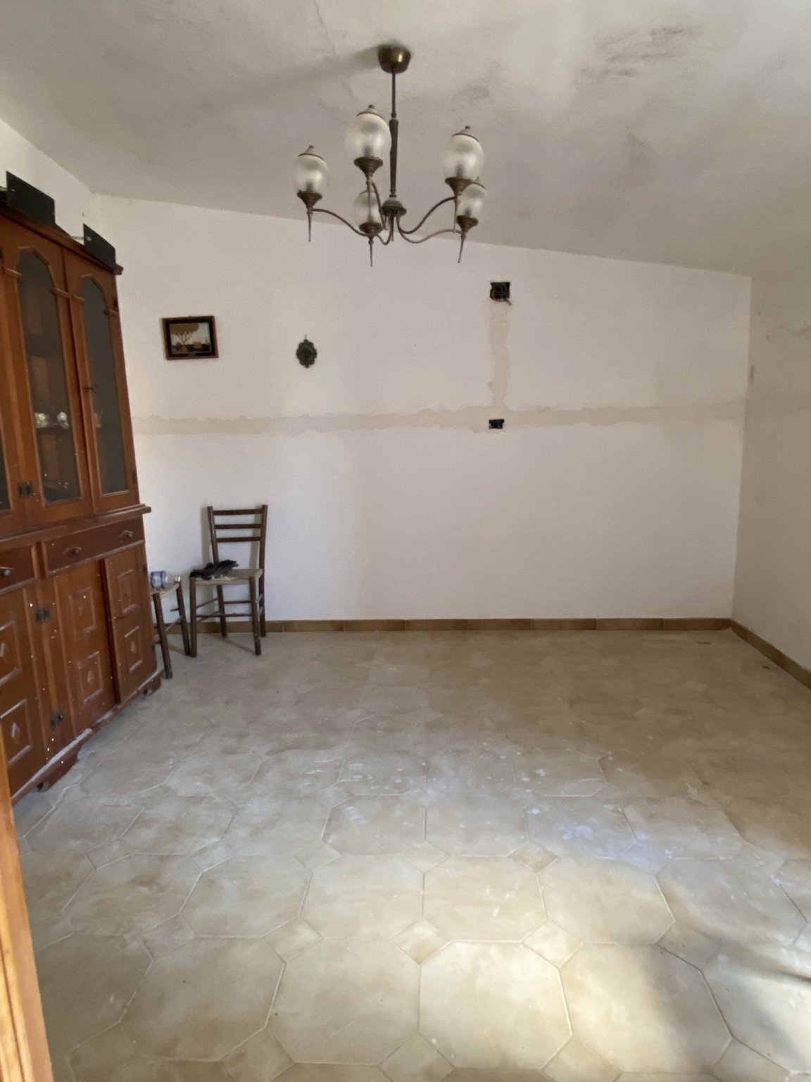 A wooden cupboard and hanging light above a tiled floor.