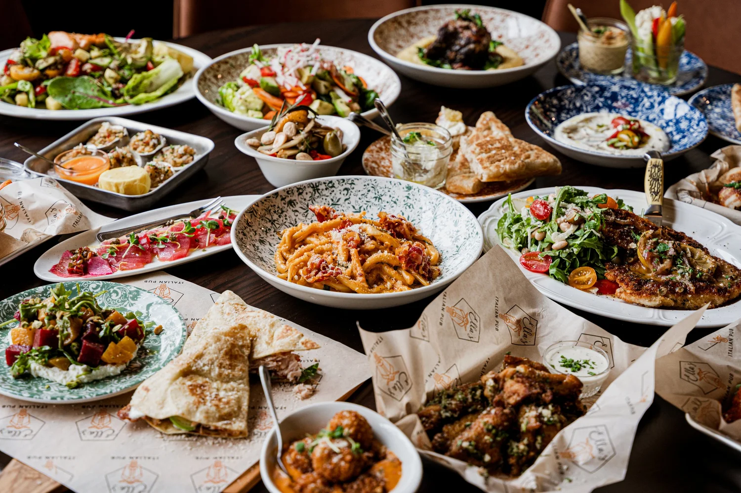 A table at Ella’s with pasta, salads, shareable dishes, and Italian pub favorites