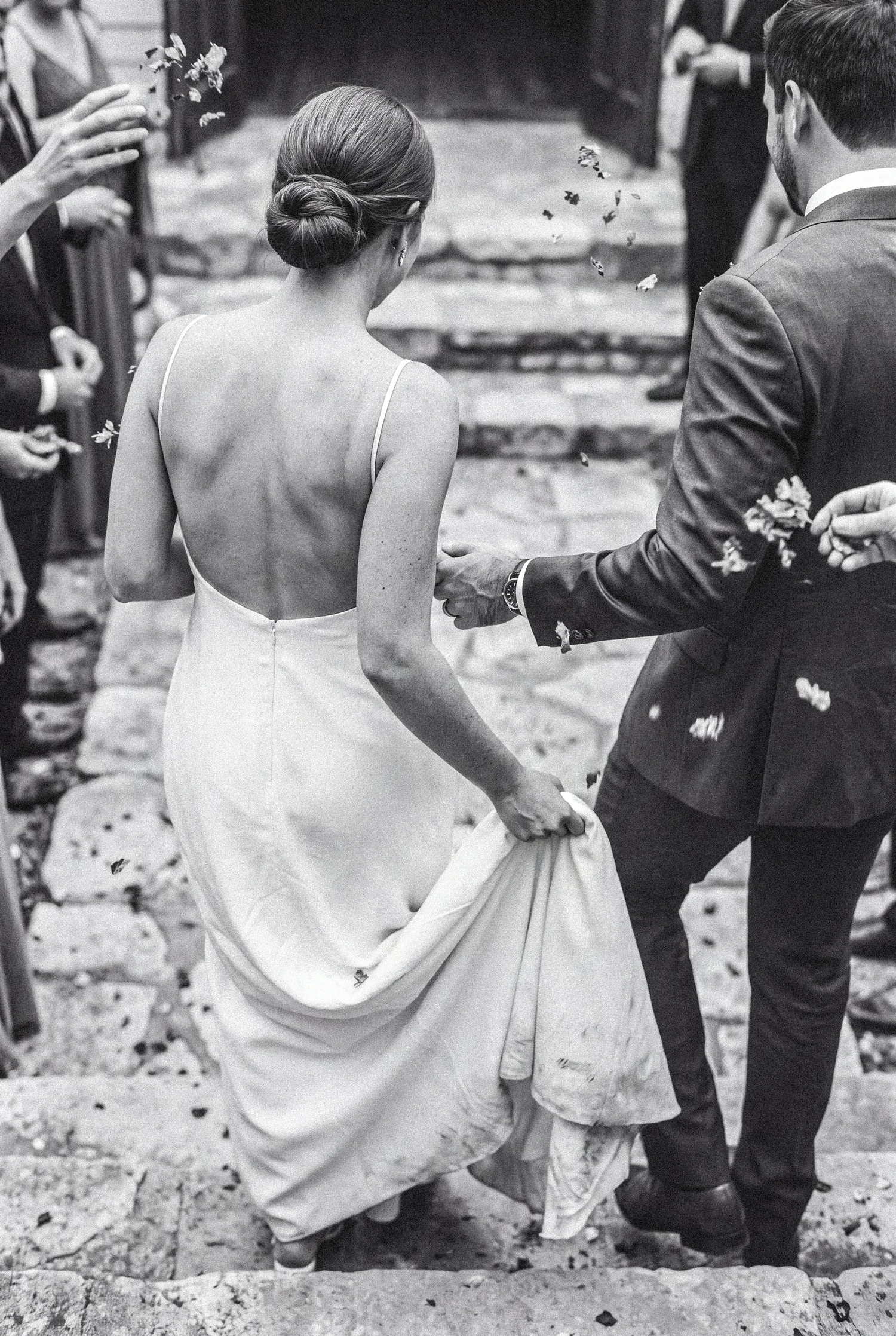 A newly married couple walks out beneath a shaded garden archway