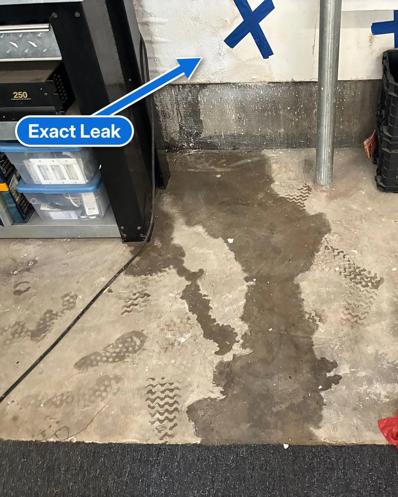 Water running across a garage floor from a leak inside the wall