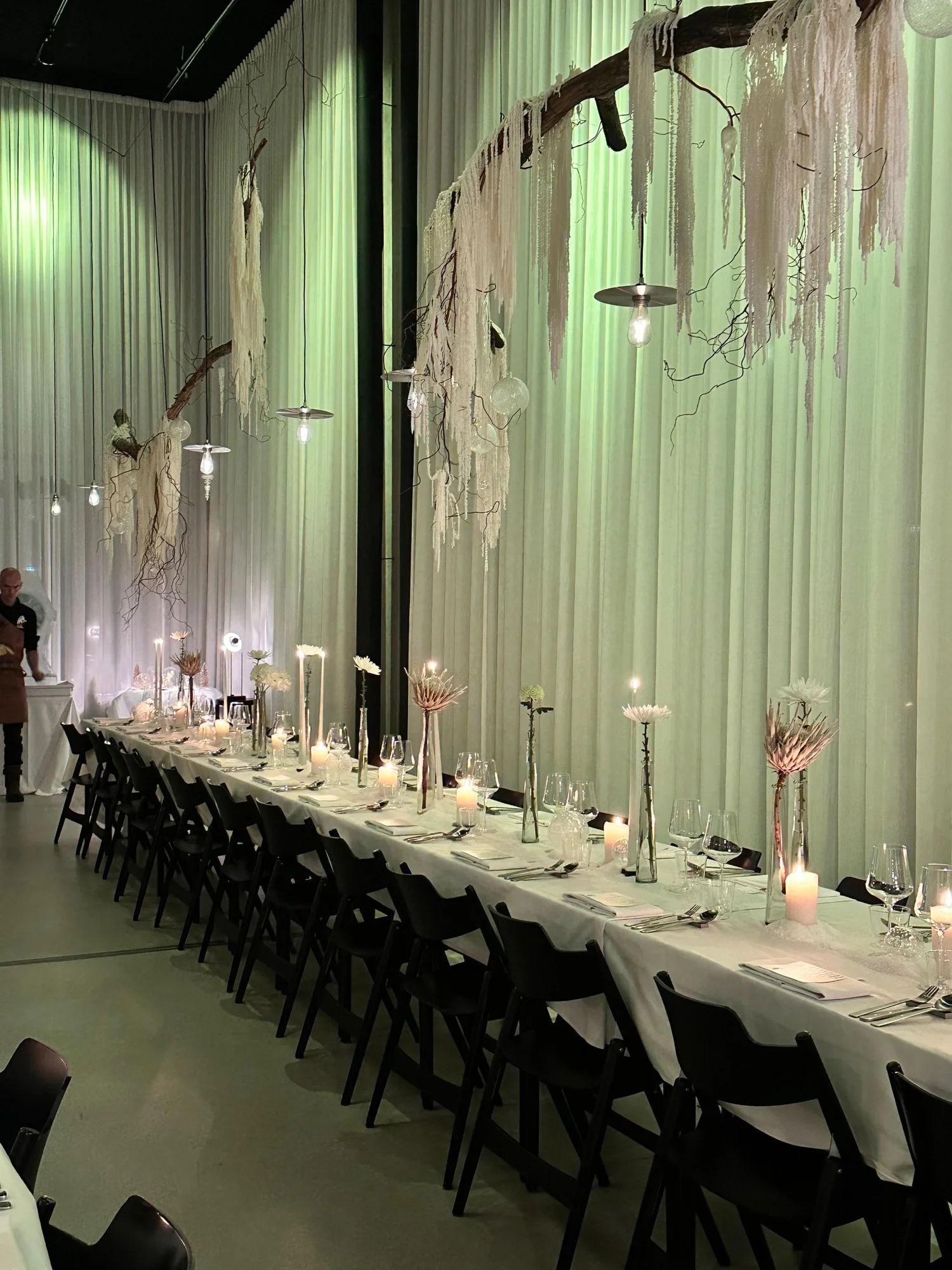 Lange tafel met wit linnen, kaarsen en winterdecor bij Copain