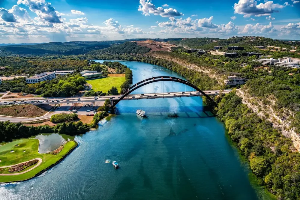 Aerial view of the Pennybacker Bridge over Lake Austin with hills and trees