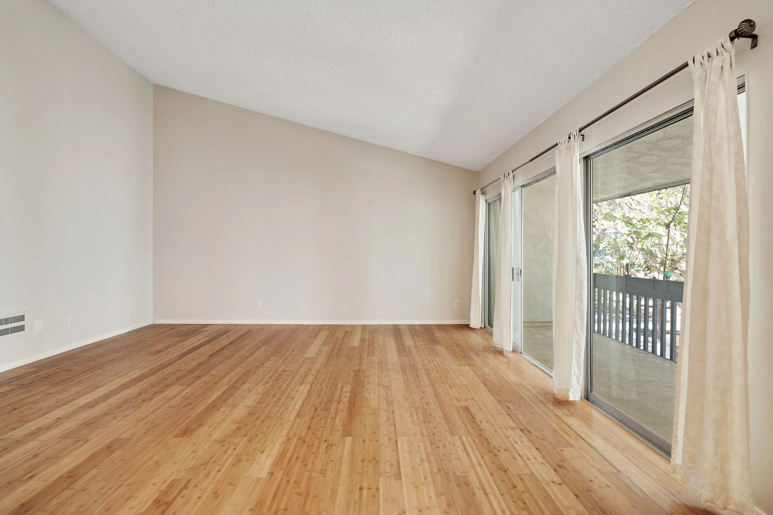 Living room as is, with bamboo floors and sliding doors to the balcony
