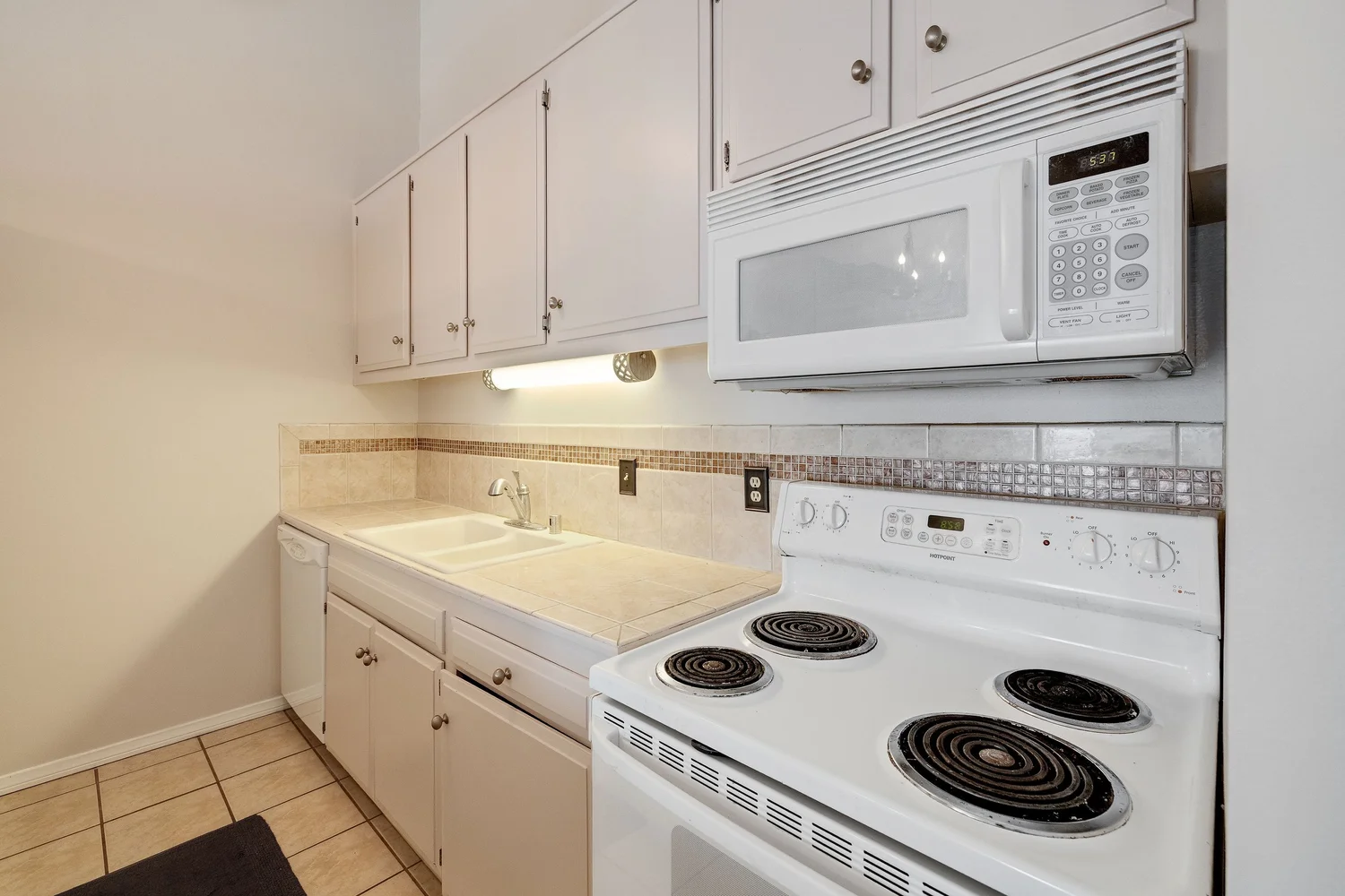 Kitchen with an electric range, microwave and tile counters