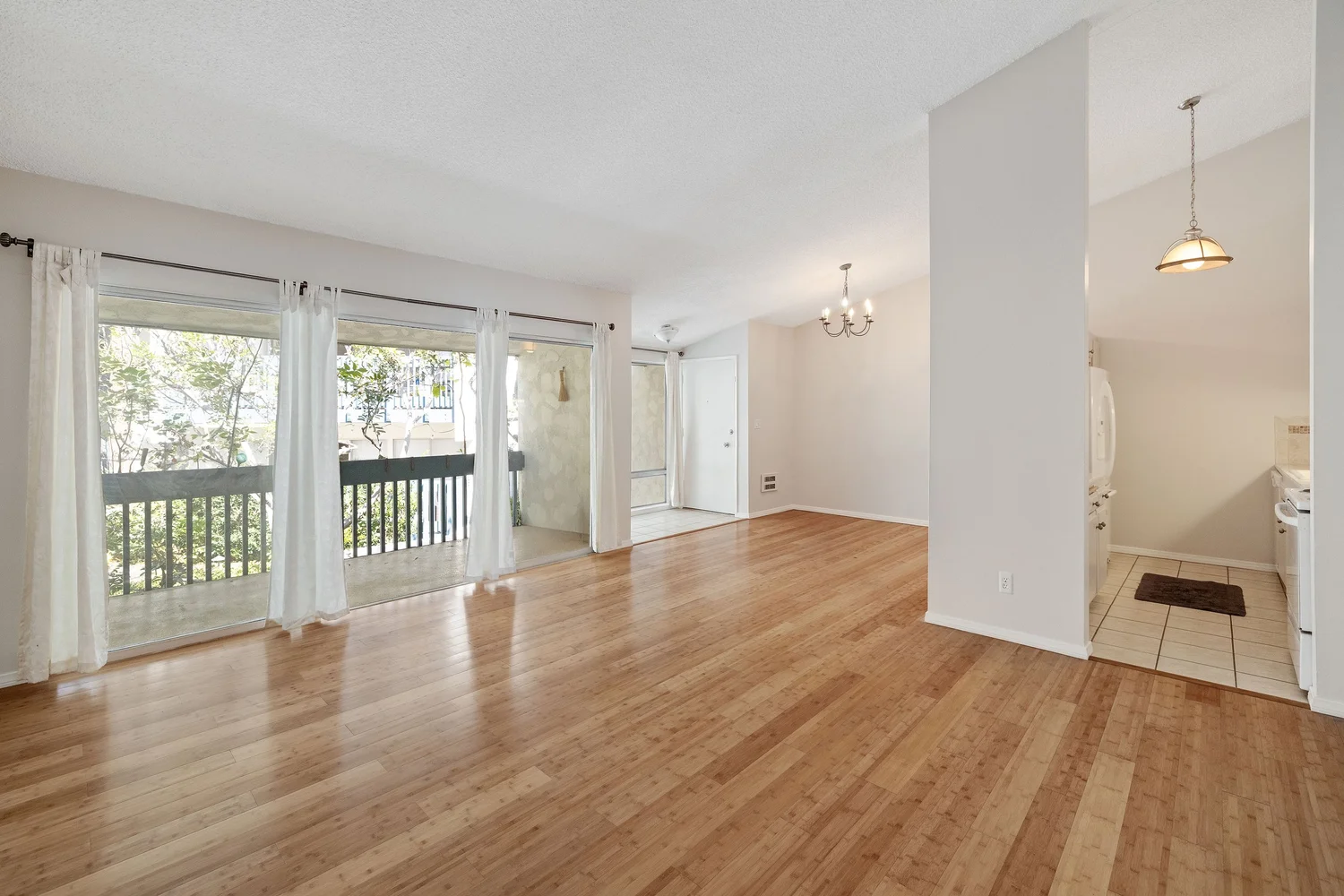 Living room with bamboo floors and sliding doors, the kitchen at right