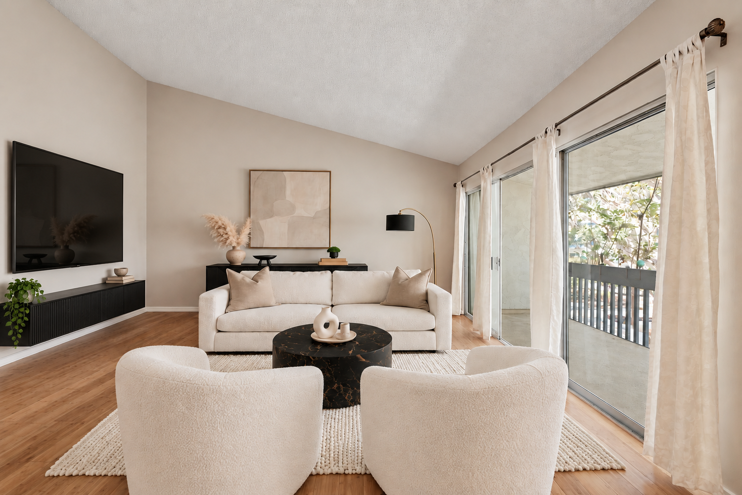 Living room with a sofa, two lounge chairs and sliding doors to the balcony, virtually staged