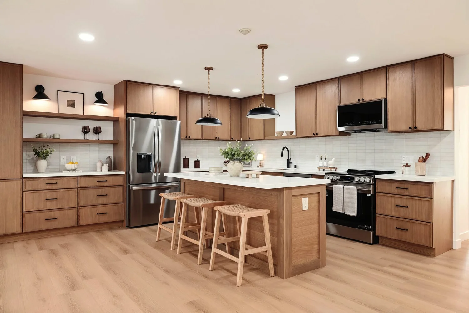 A staged kitchen with oak cabinetry and an island with stools