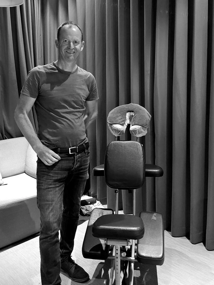 Estuary therapist Justin standing by his massage chair, ready for event guests