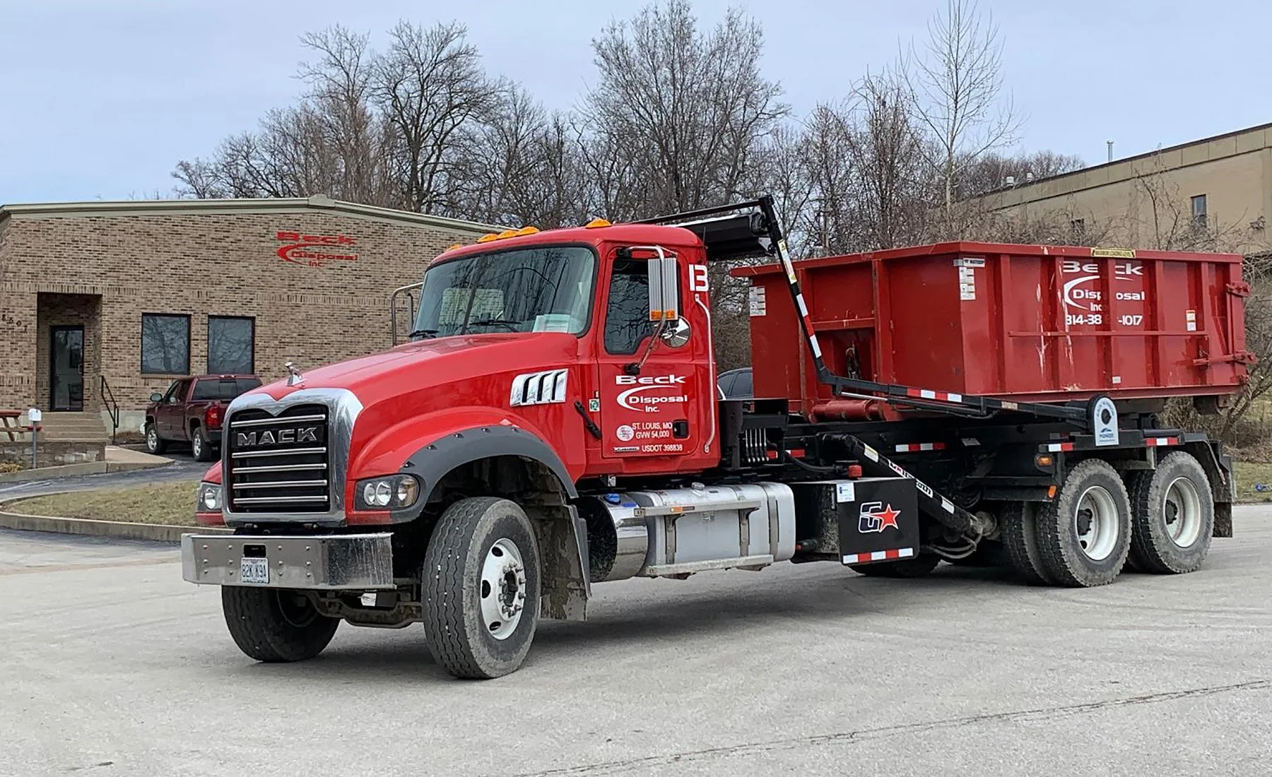 Red Beck Disposal roll-off truck and container outside the company building