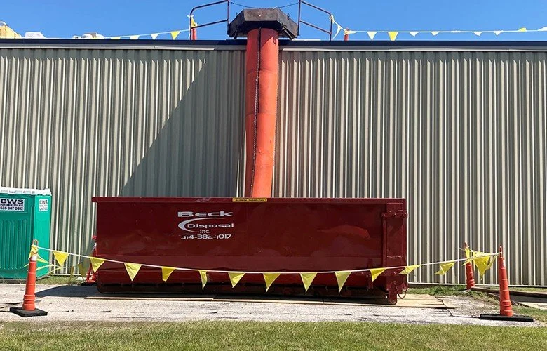 Beck open-top container beneath a debris chute beside a commercial building