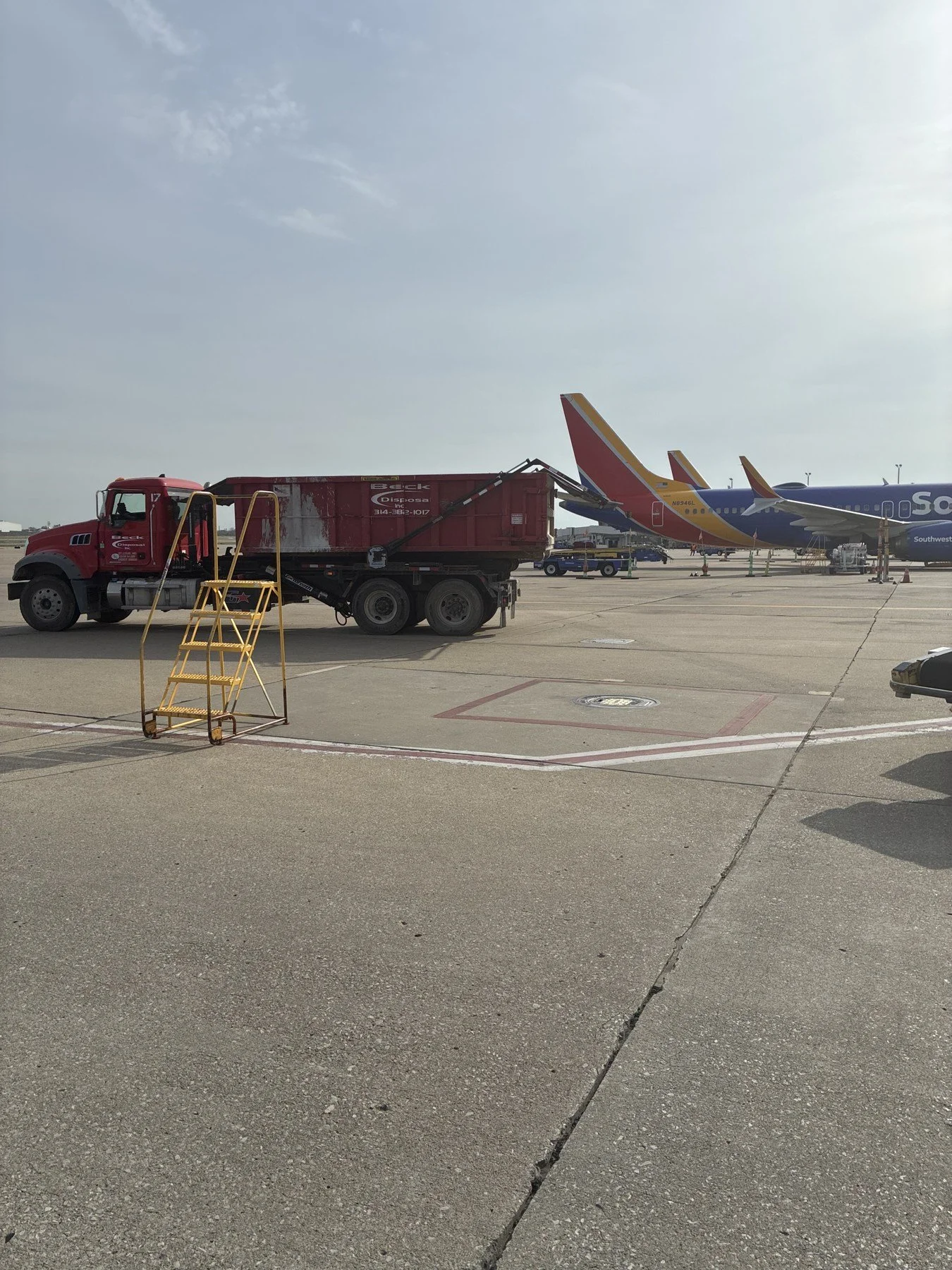 Beck roll-off truck and container on an airport apron with aircraft in the background